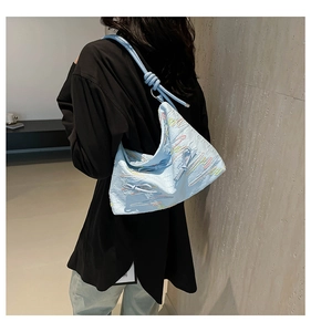 Detail of light blue tote bag featuring pleated texture and colorful embroidery accents
