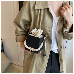 Detail of black mini box bag featuring a pearl handle and drawstring inner pouch