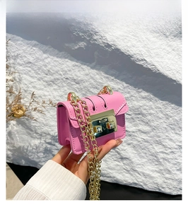 Close-up of pink PU leather mini square bag with golden chain and metallic lock