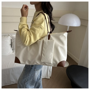 Detail of a large beige nylon tote bag with brown leather accents and small pouch