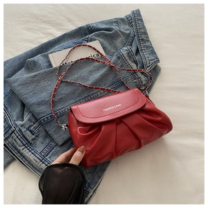 Détail du sac plissé rouge avec bandoulière chaîne sur fond de veste en jean bleu