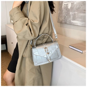 Chic silver textured handbag styled with a crossbody strap in a minimalist interior setting
