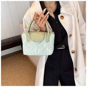 Detail of mint green quilted bucket bag with top handle and fashion print embroidery
