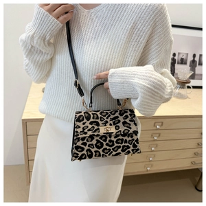Detail of leopard print crossbody bag with black handle and gold twist lock closure