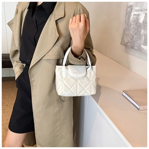 Close-up of white quilted bucket bag with Fashion & Bags logo on the leather flap