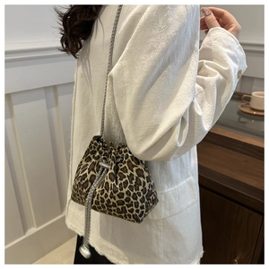Detailed view of the leopard print bucket bag with metal chain strap and drawstring closure