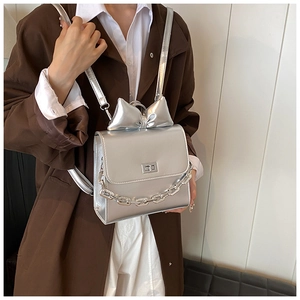 Detail of silver metallic backpack with oversized bow decoration and metal chain strap