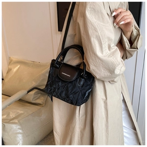 Close-up of black quilted bucket bag with diamond stitching and adjustable shoulder strap