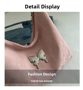 Detail of light pink pleated handbag featuring a silver Y2K liquid metal butterfly