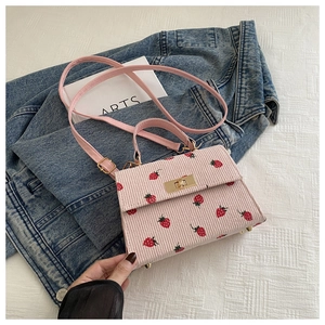 Detail of pink corduroy crossbody bag with strawberry print and gold metal twist lock