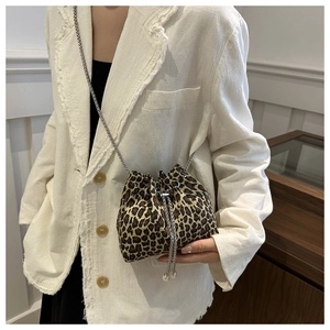 Close-up of leopard print drawstring bucket bag with silver chain strap on model