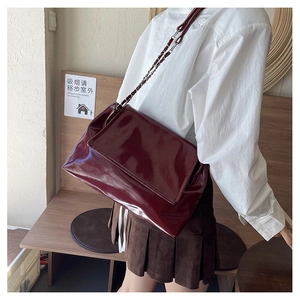Detail of the glossy dark red patent leather shoulder bag with a metal chain strap