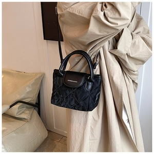 Detail of black quilted leather handbag with top handle and Fashion & Bags text