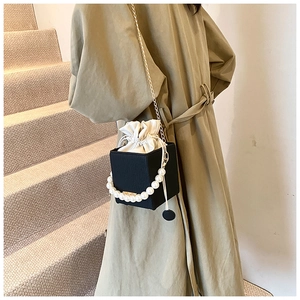 Detail of black textured leather bag with large pearl handle and metal chain strap