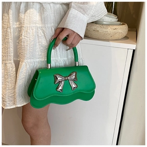 Détail d'un sac à main vert avec nœud argenté et bordure ondulée élégante