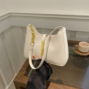 Sac à bandoulière blanc crème à la mode avec chaîne dorée sur une table en bois