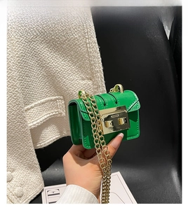 Close-up of a mini green leather chain bag with a gold metal buckle and textured finish
