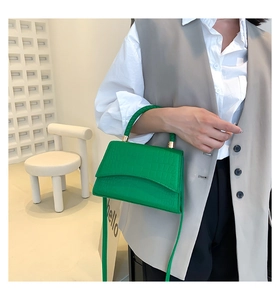 Detail of bright green crocodile embossed handbag with woven handle and gold hardware