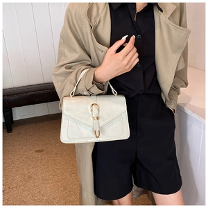 Close-up of stylish off-white structured handbag with golden horseshoe buckle detail