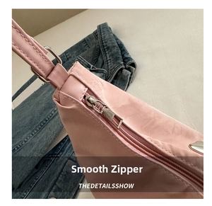 Close-up of smooth silver metal zipper on the pink embroidered nylon shoulder bag