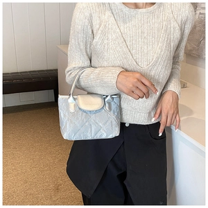 Detail of silver quilted handbag showing glossy metallic finish and handle design