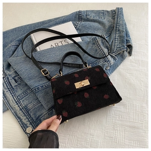 Detail of black corduroy crossbody bag with strawberry pattern and gold metal lock
