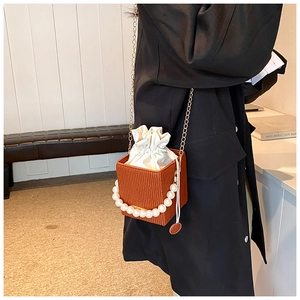 Detail of caramel crossbody bag with ripple texture, gold chain and large pearl handle