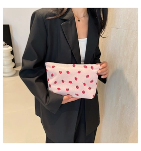 Detailed texture of pink corduroy handbag featuring cute red strawberry prints