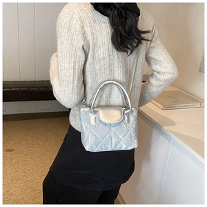 Detail of silver quilted bucket bag with crossbody strap on a model in modern setting