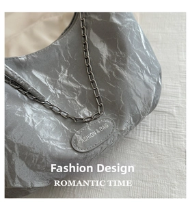 Detail of silver metallic wrinkled texture bag with chain strap and oval fashion plaque