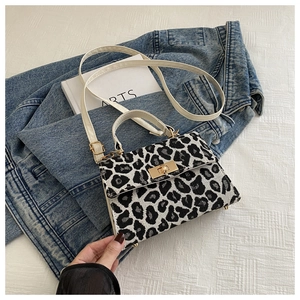 Detail of leopard print crossbody bag featuring a gold metal twist lock and white leather handle
