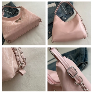 Detail of pink hobo bag featuring a silver butterfly charm and chain shoulder strap