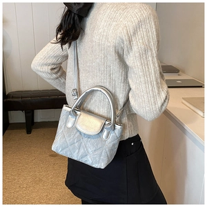 Detail of silver quilted bucket bag featuring metallic faux leather and crossbody strap