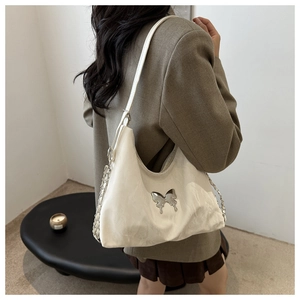 Detail of white PU leather shoulder bag with silver butterfly clasp and chain strap