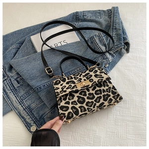 Detail of leopard print mini crossbody bag with gold twist lock on denim background