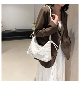 Detail of white quilted underarm bag with wave embroidery and 3D bow on shoulder