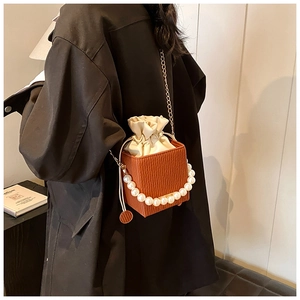 Detail of retro brown box bag with large pearls and golden chain on fashion model