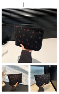 Close-up of black corduroy tote bag featuring red strawberry embroidery patterns