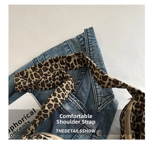 Close-up of leopard print wide strap on a denim jacket showing textile texture