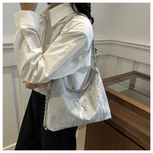 Detail of silver pleated shoulder bag with metallic butterfly and chain strap