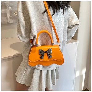 Détail du sac orange avec nœud en métal argenté et design à bordure festonnée unique