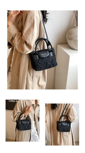Close-up of quilted black bucket bag with fashion lettering and leather handle details