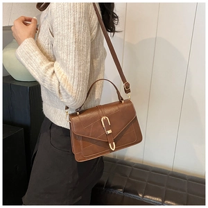 Lifestyle view of brown leather crossbody bag with gold U-shaped buckle on a model