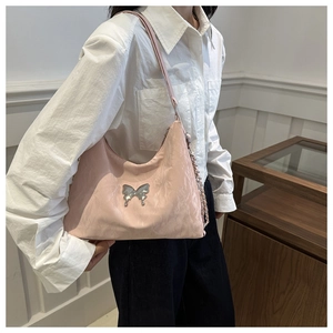 Detail of pink nylon shoulder bag featuring a silver butterfly charm and crinkled texture