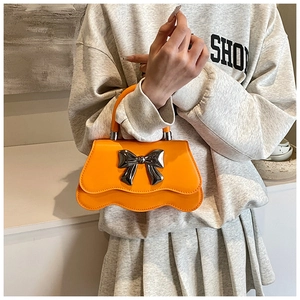 Détail du sac à main orange avec noeud métallique et bord inférieur ondulé