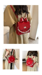 Detail of red glossy mini backpack featuring a large bow and silver metal chain strap