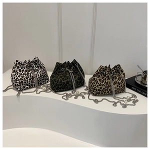 Three leopard print bucket bags with silver chains and pearl charms on curved pedestal