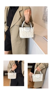 Detailed view of white quilted bucket bag with polished finish and logo flap