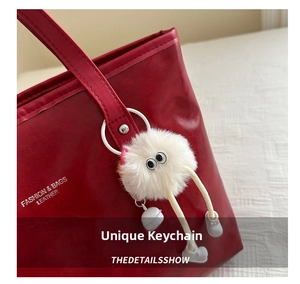 Detail of red leather tote bag featuring fashion embossing and white monster plush charm