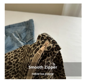 Close-up of the smooth golden metal zipper detail on the leopard print canvas tote bag